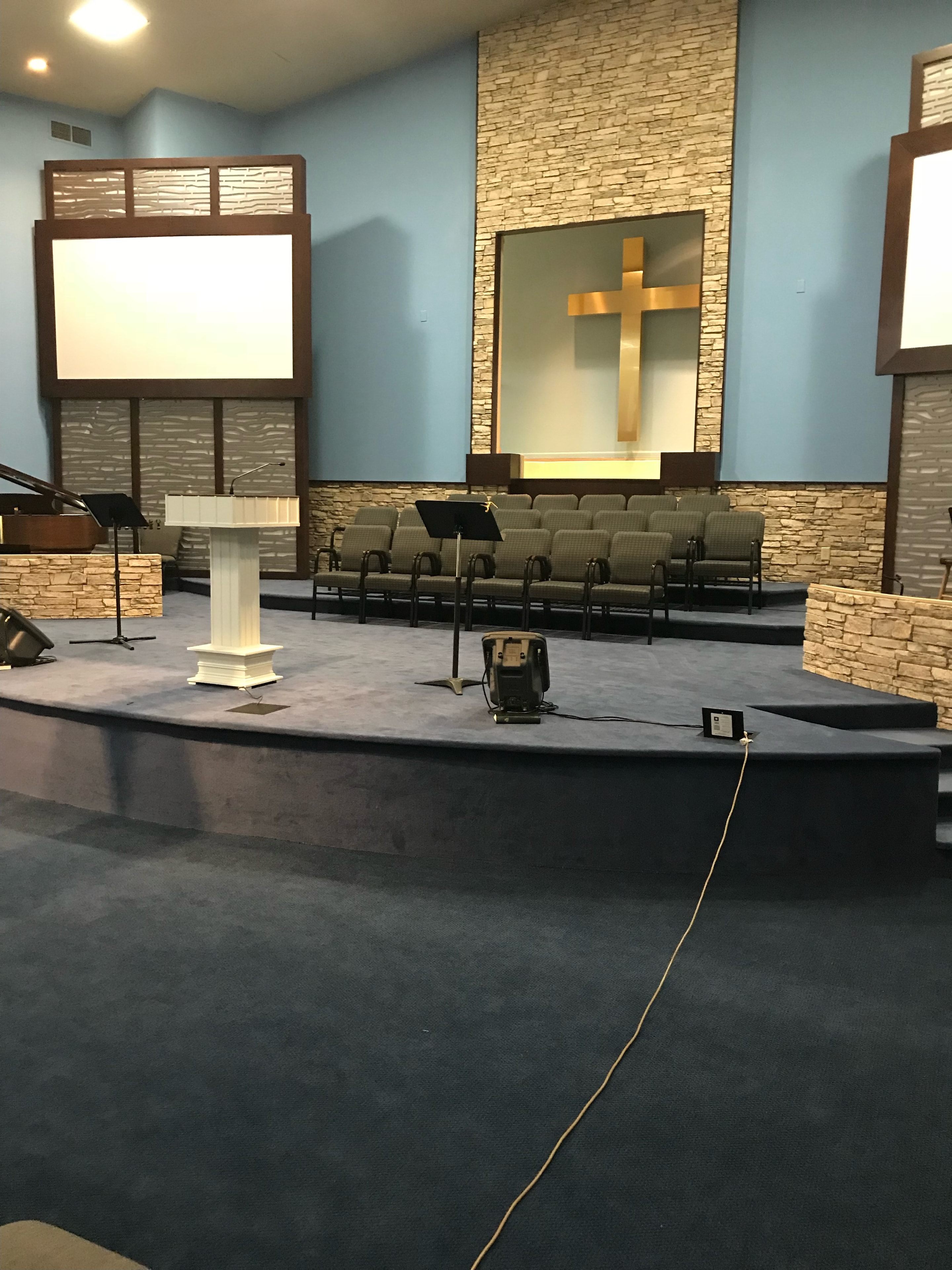 Sanctuary with blue walls, gold cross, and dark carpet
