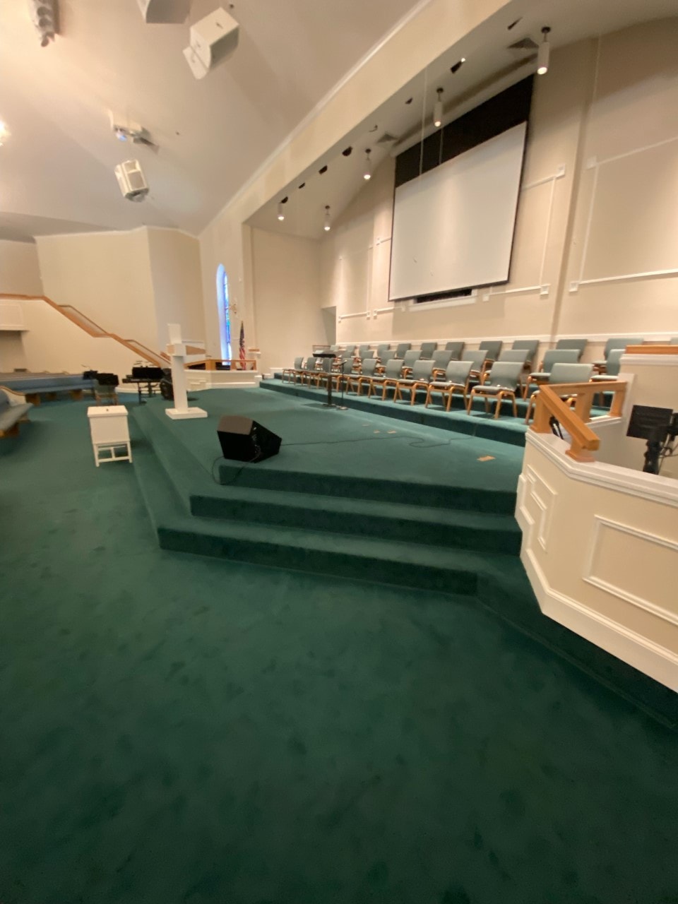Sanctuary with rich teal carpet, choir seating, and stained glass