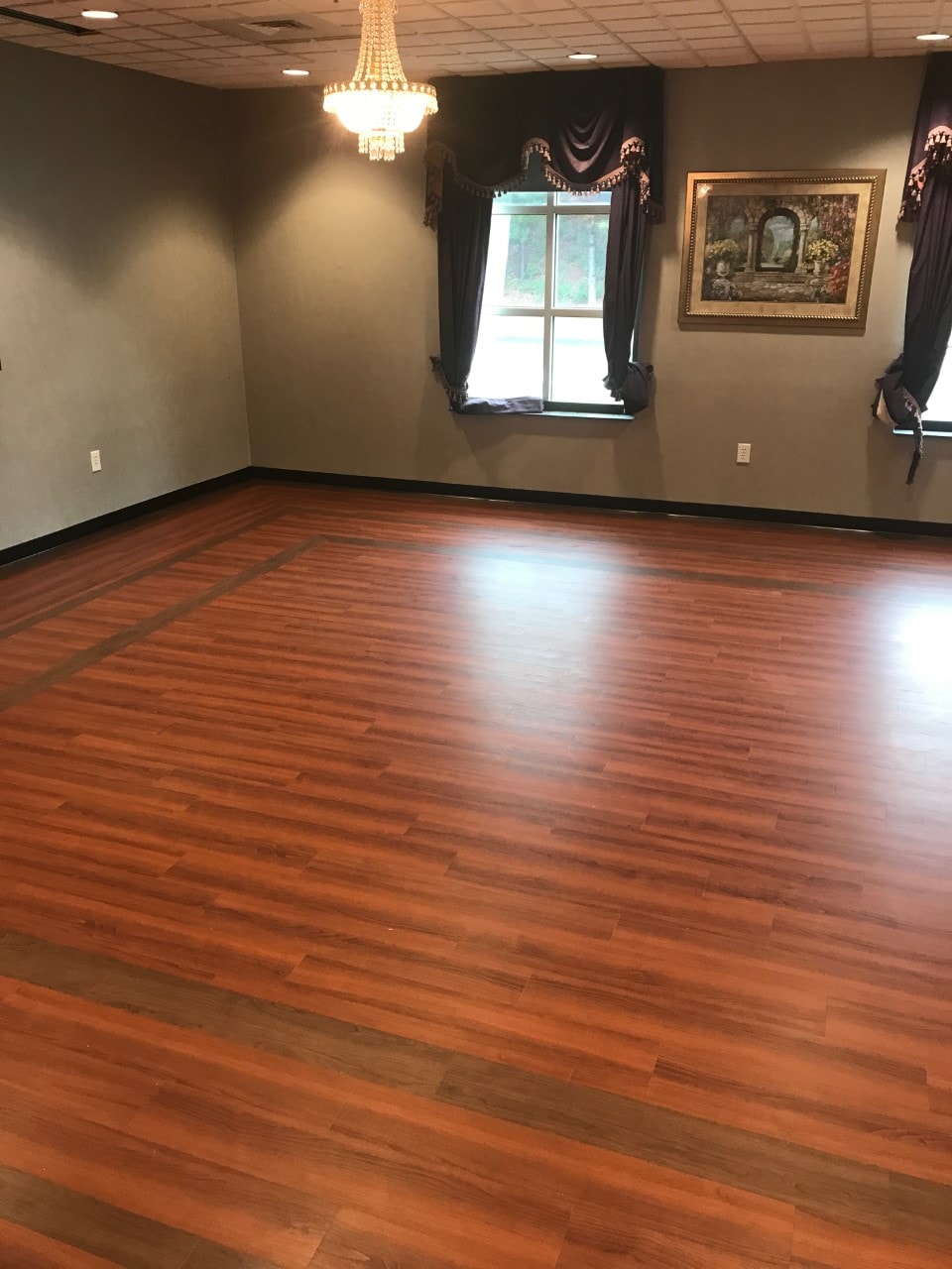 Elegant event room with rich hardwood flooring and chandelier
