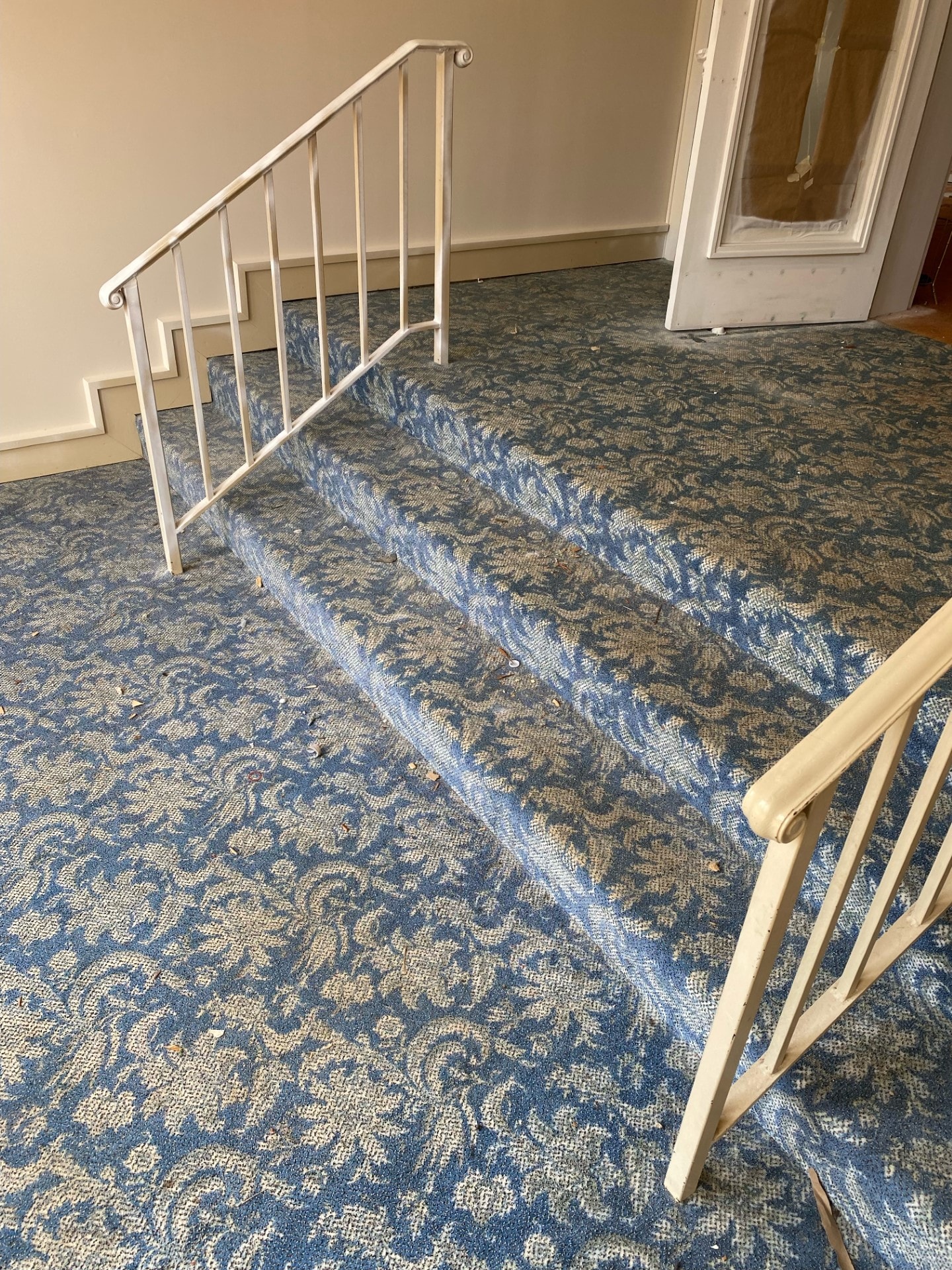 Staircase with ornate blue and grey patterned carpet